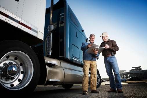 Two men standing in front of a semi truck.