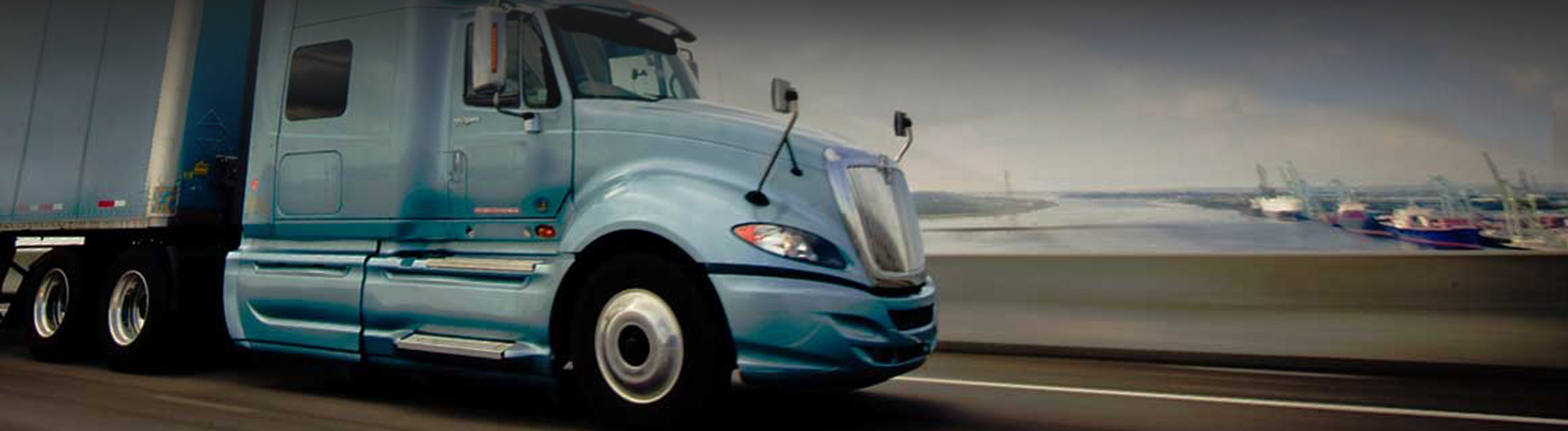 A blue semi truck driving down a highway.