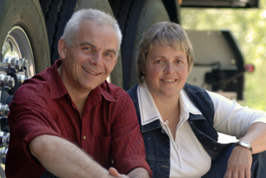 Two persons sitting on the ground and smiling